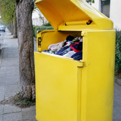 Conteneur jaune de textile au couvercle ouvert sur trottoir