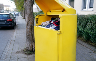 Conteneur jaune de textile au couvercle ouvert sur trottoir