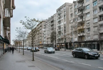 Grands immeubles gris alignés le long d'une avenue passante