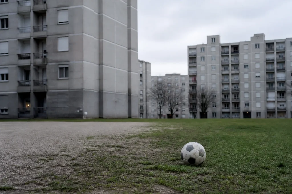 Immeubles gris et ballon de foot sur un terrain