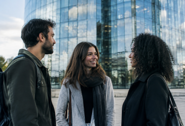 Trois personnes debout devant une tour vitree scintillante