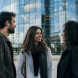 Trois personnes debout devant une tour vitree scintillante