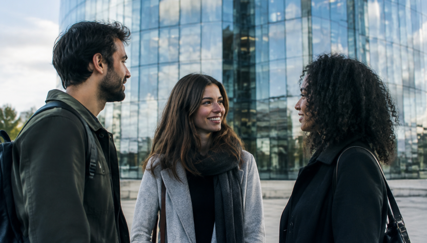 Trois personnes debout devant une tour vitree scintillante