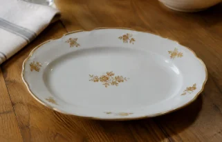 Plat blanc garni de fleurettes dorees pose sur table