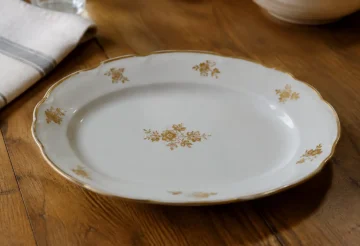 Plat blanc garni de fleurettes dorees pose sur table