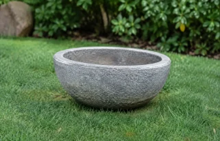 Vasque ronde en pierre grise posee sur pelouse verte