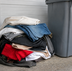 Vetements usages empiles devant bac recyclage gris