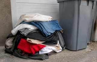 Vetements usages empiles devant bac recyclage gris