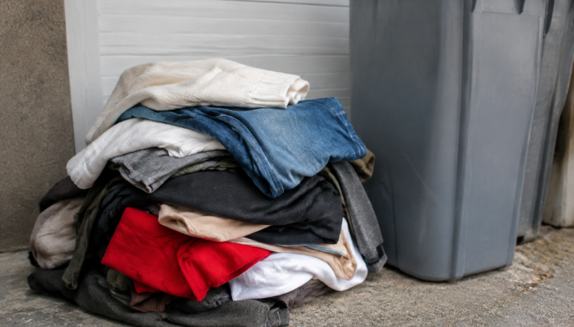 Vetements usages empiles devant bac recyclage gris